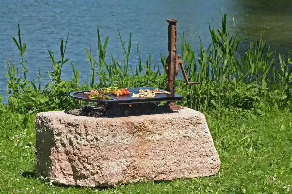 Grill aus Naturstein mit höhenverstellbarer Grillplatte mit Winde