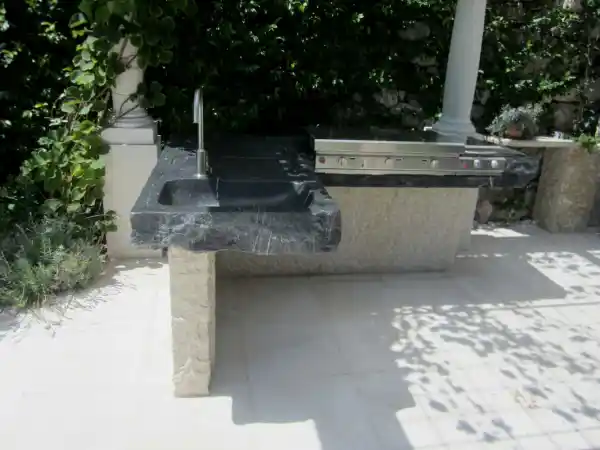 Combinazione barbecue bicolore in pietra naturale con barbecue a gas, mensola e lavabo su misura.
