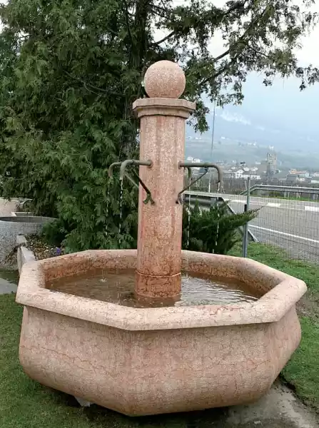 Grande fontana con colonna centrale in pietra calcarea rossa con prese d'acqua forgiate a mano