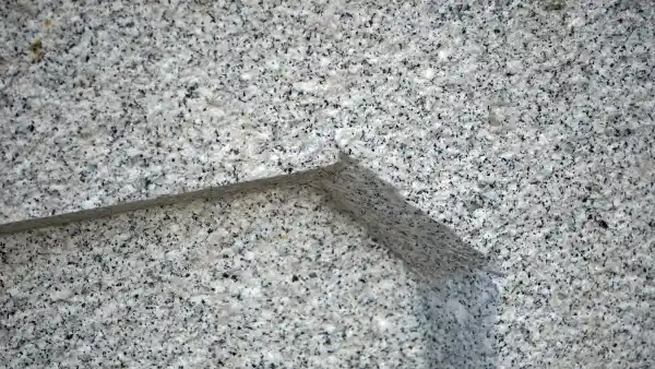 Detail des Brunnens, die Oberfläche ist gestockt und Felder wurden auf der Außenseite vertieft.