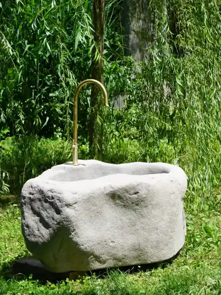 Naturbelassener Gartenbrunnen aus Porphyr Naturstein mit handgeschmiedetem Wasserhahn aus Messing