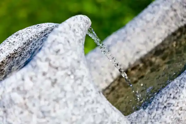 Gioco d'acqua di una fontana in pietra naturale realizzata con grande cura da un masso di granito dell'Alto Adige.