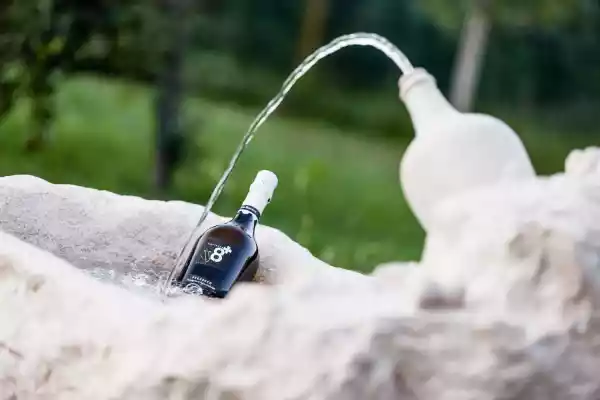 Garten-Brunnen mit Prosecco-Flasche aus einem Kalksteinfindling