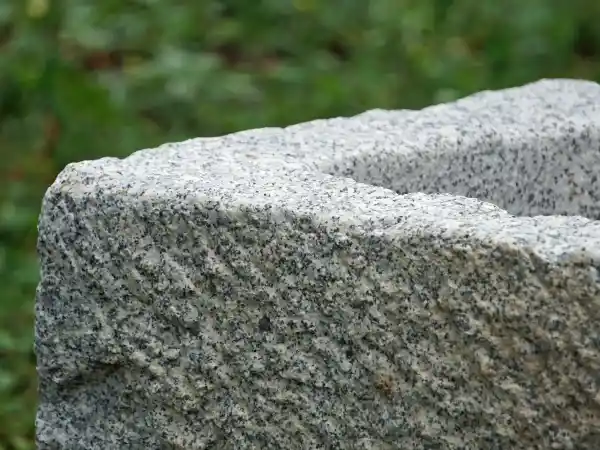 Rustikal behauener Rand des Beckens aus Naturstein Granit