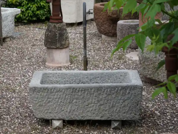Alter Steintrog aus grauem Kalkstein mit Wasserhahn