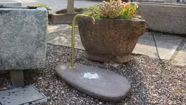 Kleine Wasserstelle aus Naturstein mit Anschluss für den Gartenschlauch