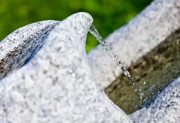 Wasserspiel eines Brunnens aus Naturstein, der mit großer Sorgfalt aus einem Brixner Granitbachstein aus Südtirol gefertigt wurde.